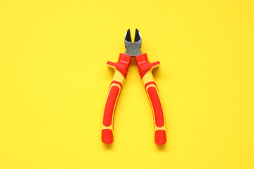 Diagonal pliers on yellow background, top view