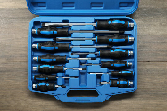 Set of screwdrivers in open toolbox on wooden table, top view