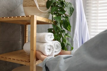 Fototapeta na wymiar Woman putting rolled towels onto shelf indoors, closeup