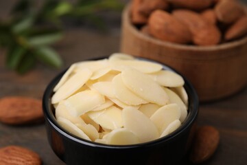 Fresh almond flakes in bowl on table, closeup