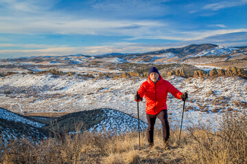 senior male hiker reaching top of a hill at foothills of Rocky Mountains - winter scenery at...