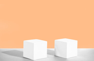 Cosmetic peach fuzz background with geometric shapes. Two white cement cubic podiums. Mockup for the demonstration of cosmetic products
