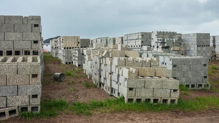 Fotobehang Stacks of concrete blocks, with rain stains, for construction of single-family houses in a suburban residential development (once ranchland) on an overcast morning in springtime, southwest Florida © Kenneth
