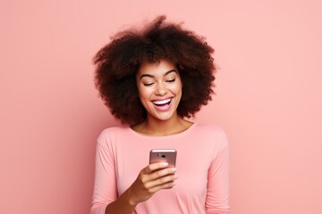 Joyful woman using smartphone on pink background