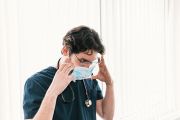 A healthcare professional is captured in the act of adjusting a surgical mask, emphasizing the importance of safety measures