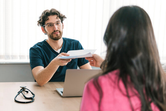 In a clinic setting, a doctor is seen providing important medical paperwork to a patient, highlighting the collaborative care process