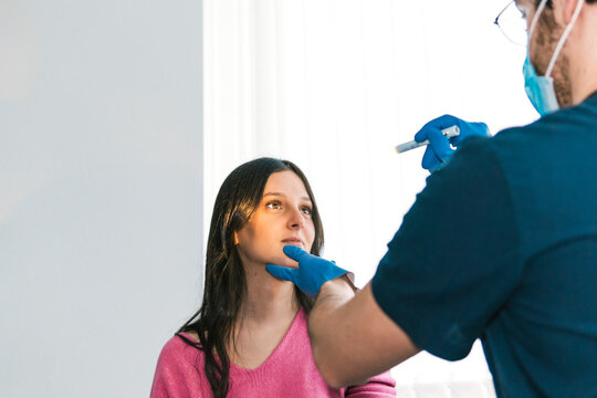 A focused doctor examines the throat of a patient using a medical light, an essential part of a routine ENT checkup