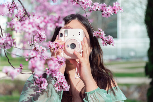 Woman capturing spring blossoms with a pink camera