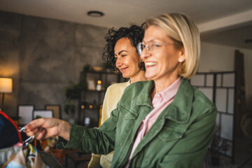 two mature women female friends at home choose sort clothes on hanger