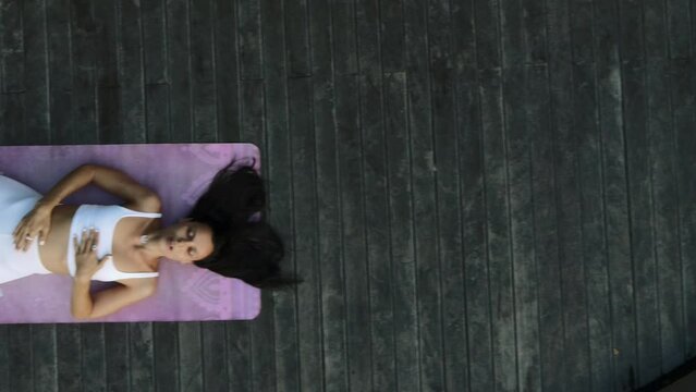 A beautiful young girl of European appearance, brunette, doing yoga, doing breathing exercises, in a stylish white yoga suit.