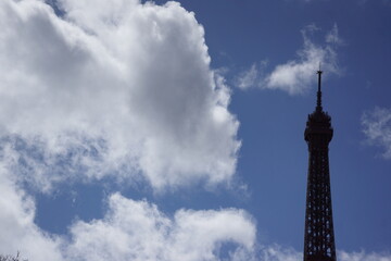 Silhouette of Eiffel Tower with large clouds and blue sky