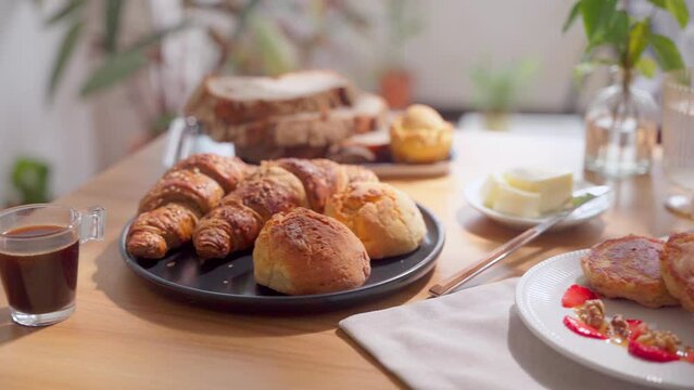 Continental breakfast set with pancakes and assorted pastry on a wooden table. Vertical shot, camera pan