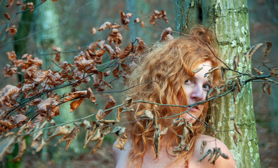 sensual portrait of young beautiful sexy naked redhead woman in the autumn foliage leaves in the sunny forest