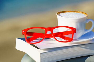 Coffee cup and book on sea coast