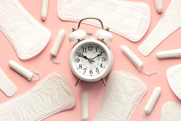 Top view of sanitary pads, menstrual tampons and white alarm clock. Concept of menstruation and menopause