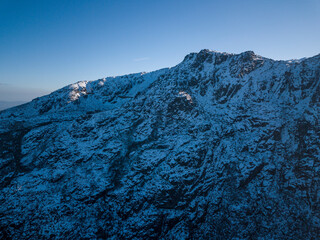 Aerial view of snow-capped mountain peaks at sunset.