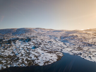 Aerial view of snow-covered landscape with lake at sunset time. Viriato Lake. Serra da Estrela, Portugal