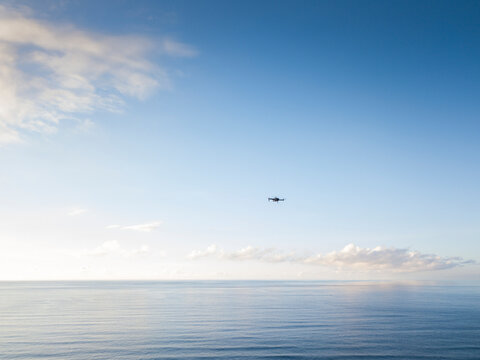 Seascape with a drone flying in the blue sky and clouds.