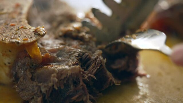 Close-up of fork shredding meat, macro preparation of food meal