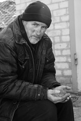 Fototapeta premium Poor homeless senior man holding coins outdoors. Black and white effect