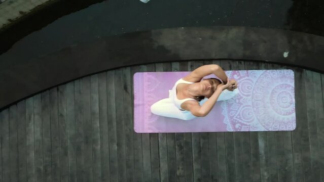 A beautiful young girl of European appearance, brunette, doing yoga, doing breathing exercises, in a stylish white yoga suit.