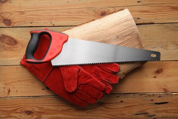 Saw with colorful handle and gloves on wooden background, top view