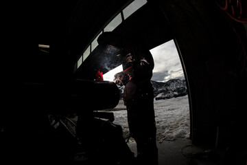 Dusk Silhouette of a Rugged Outdoorsman Welding in a Snowy Landscape