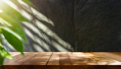 Empty wooden table next to a black wall, dark tones, with plant leaves and shadows outdoors. Brown...