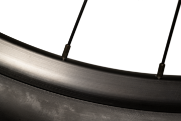 Macro image of a new clean bicycle wheel with a black rim and a transparent background. Light highlights the rim and parts of two spokes.
