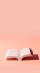 A book is open on a pink background. The book is a paperback and is open to a page with a white...