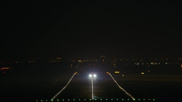 An airplane accelerates along the runway, lifting off into the night sky