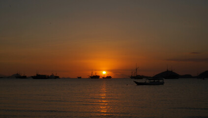 View of the sunset with the silhouettes of ships in the distance