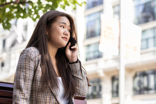 Young asian woman talking on the phone in the city