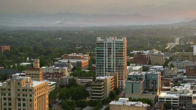 North Carolina Appalachian city Asheville with downtown architecture and Blue Ridge Mountain hills in distance at sunset. US travel destination