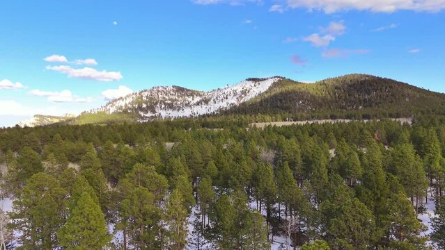 Drone footage of Arizona mountain in the winter time with the snow on the top. Winter forest in the mountings in the morning time.