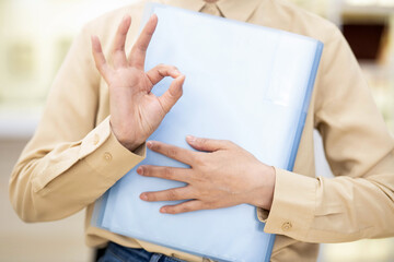 Obraz na płótnie Canvas Office white-collar worker holding folder and making OK gesture