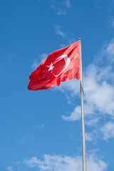 Flag of the Republic of Turkey on a flagpole unfurled in the wind against the blue sky