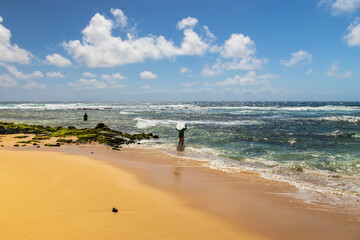 Fototapeta na wymiar a man surfing at Sandy Beach with vast blue ocean water, rocks covered in lush green algae, crashing waves, blue sky and clouds in Honolulu Hawaii USA