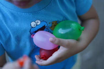 水風船を抱える子供 / Child holding a water balloon
