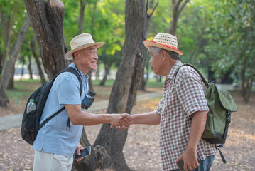 Naklejka na ściany i meble Asian male tourist Shake hands with the tour guide and smile happily. Feeling delighted with the kindness and generosity of the service. Travel concept in retirement
