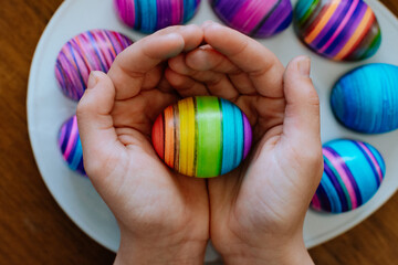 Fototapeta na wymiar Hands Holding a Rainbow Easter Egg 