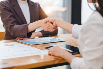 Two professionals completing a successful negotiation with a handshake, with documents and digital...