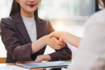 Two confident businesswomen seal a professional deal with a firm handshake in an office.