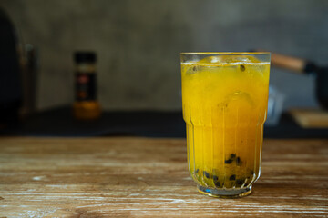 Fresh Look Drink in Yellow Color with Passion Fruit Seeds sinks to the bottom of the glass. Served on the Wooden Table