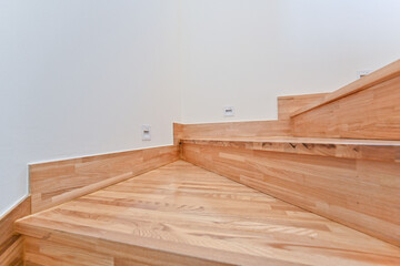 A bright wooden colored staircase that matches a clean and pretty interior