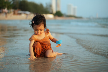happy toddler baby girl playing toy and water on sea beach