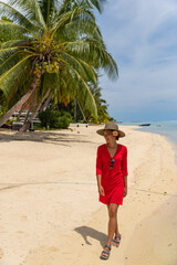 Travel woman walking on beach smiling in sundress and sunhat on Matira Beach, Bora Bora, Tahiti,...