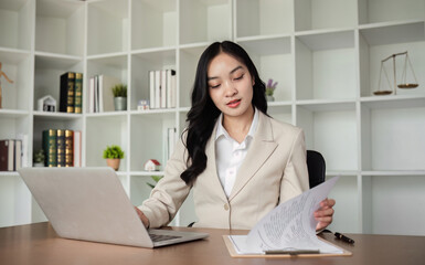 A female Asian lawyer reviews business and real estate laws. Legal consultants provide legal advice and guidance online via laptops in lawyers' offices.