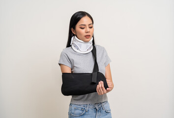 Depressed upset woman suffering from pain. Broken arm. Asian woman put on plaster bandage cast splint. Patient wearing sling support arm after accident injury. life insurance and accident - obrazy, fototapety, plakaty