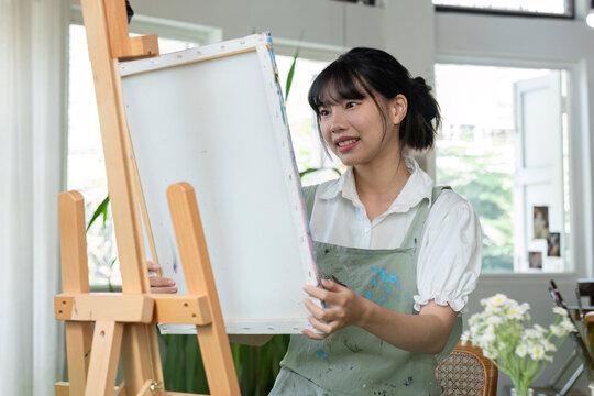 An artistic girl paints with acrylic paints on canvas with determination.